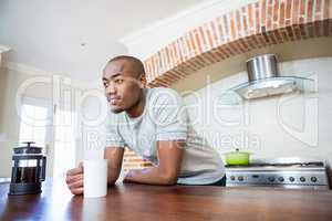 Young man leaning on the table holding coffee mug