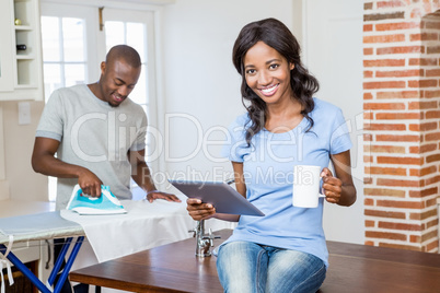 Young woman holding coffee mug and using digital tablet