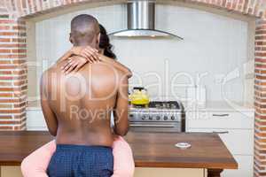 Young couple cuddling on kitchen worktop