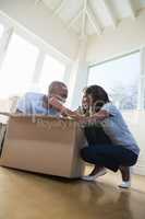 Young couple having fun while unpacking box