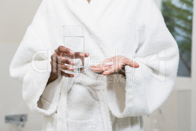 Beautiful woman holding pill and glass of water
