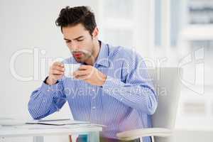 Businessman blowing a hot cup of coffee