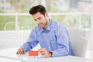 Businessman looking at a model house and writing on paper