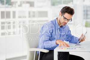 Businessman looking at document and using digital tablet