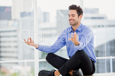 Businessman meditating in lotus pose