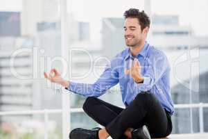 Businessman meditating in lotus pose