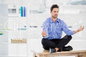 Businessman meditating in lotus pose