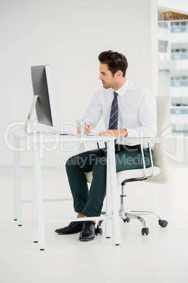 Businessman using computer and taking notes