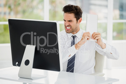 Frustrated businessman holding keyboard in anger