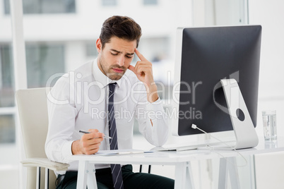 Businessman using computer and taking notes