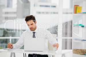 Businessman using laptop and taking notes