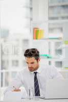 Businessman using laptop and taking notes