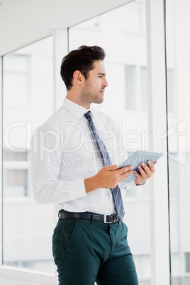 A man is holding a notebook and looking outside