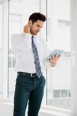 A man is holding a notebook and touching his neck