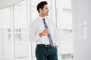 A businessman is holding a notebook and looking outside