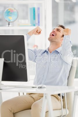 A business is sitting in front of his computer and is happy