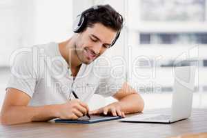 Young man using pen tablet and laptop