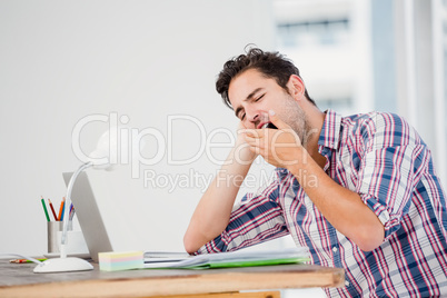 Young man yawning at his desk