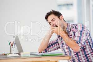 Young man yawning at his desk