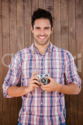 Portrait of young man standing with a digital camera