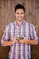 Portrait of young man standing with a digital camera