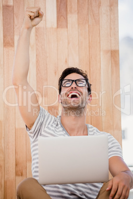 Excited man sitting on the floor and using laptop
