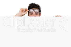 Man in spectacles hiding behind the white board