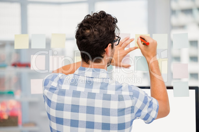 Rear view of man writing on sticky notes