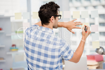 Rear view of man writing on sticky notes