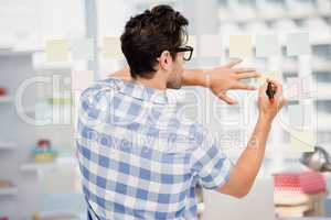 Rear view of man writing on sticky notes