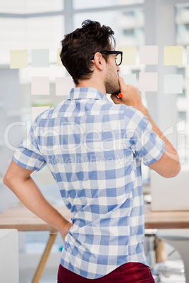 Thoughtful man reading at sticky notes on window