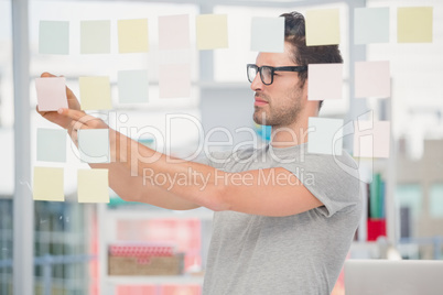 Man writing at sticky notes on window