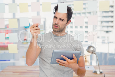 Man holding digital tablet and looking at sticky notes