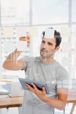 Man holding digital tablet and looking at sticky notes