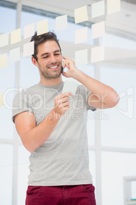 Man looking at a sticky notes while talking on phone Man looking at a sticky notes while talking on phone