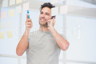 Man looking at a sticky notes while talking on phone