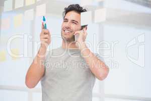 Man looking at a sticky notes while talking on phone