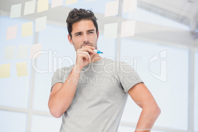 Thoughtful man looking at sticky notes on window