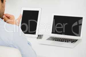 Mid-section of businessman using digital tablet with laptop on t