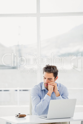 Tensed businessman sitting at table with laptop