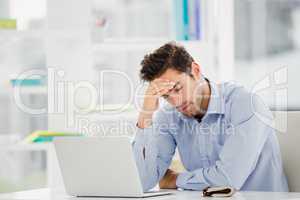 Tensed businessman sitting at table with laptop