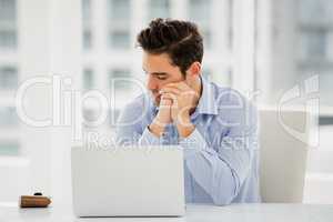 Tensed businessman sitting at table with laptop