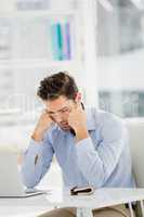 Tensed businessman sitting at table with laptop