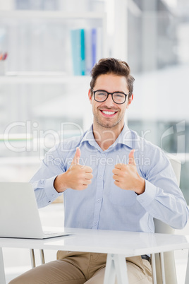 Businessman showing thumbs up while using laptop Businessman showing thumbs up while using laptop