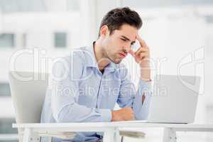 Tensed businessman sitting at table with laptop