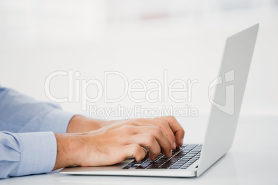 Mid-section of businessman working on laptop