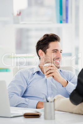 Smiling man sitting with feet on table