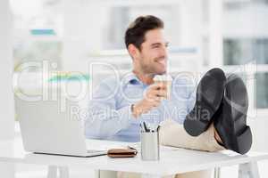 Smiling man sitting with feet on table