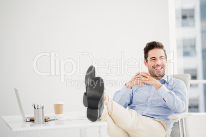 Thoughtful man sitting with feet on table