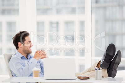 Thoughtful man sitting with feet on table
